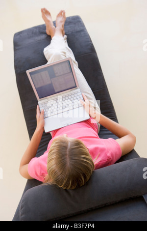 Donna seduta nella poltrona utilizzando laptop Foto Stock