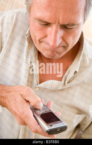 Uomo che utilizza un telefono cellulare per interni Foto Stock