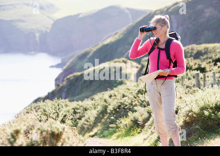 Donna su cliffside percorso utilizzando un binocolo Foto Stock