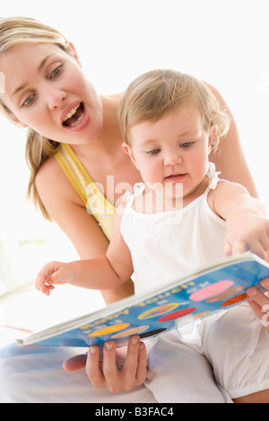 La madre e il bambino libro di lettura in ambienti chiusi e puntamento Foto Stock
