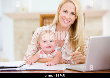 La madre e il bambino nella sala da pranzo con laptop sorridente Foto Stock