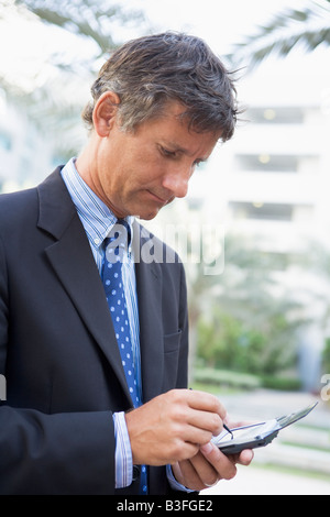 Imprenditore all'aperto utilizzando assistente digitale personale Foto Stock