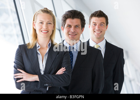 Tre gli imprenditori in piedi in corridoio sorridente Foto Stock