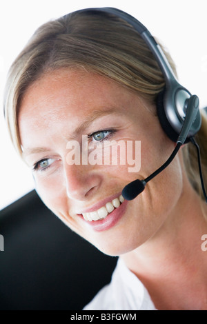 Imprenditrice di office che indossa la cuffia e sorridente Foto Stock