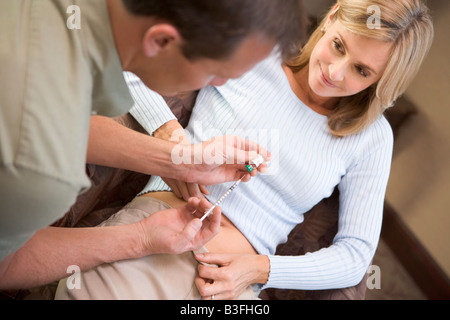 Uomo Donna aiuta iniettare farmaci per preparare per il trattamento FIV (messa a fuoco selettiva) Foto Stock