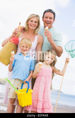 La famiglia sta in piedi in spiaggia con gelato sorridente Foto Stock