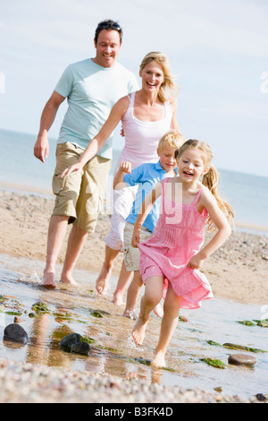 Famiglia in esecuzione presso la spiaggia di sorridere Foto Stock