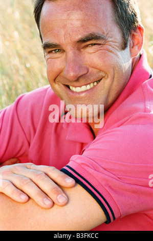 Uomo seduto all'esterno sorridente Foto Stock