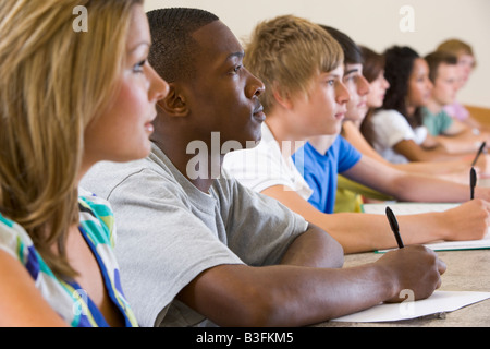 Gli studenti nella classe prestando attenzione e prendere appunti (messa a fuoco selettiva) Foto Stock