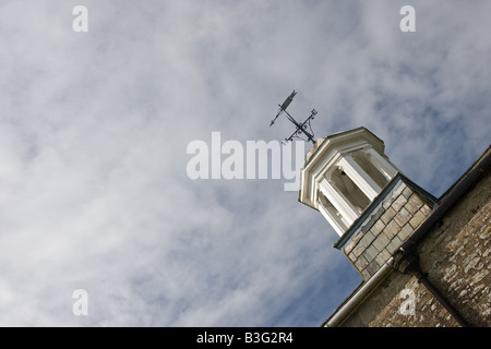 Meteo banderuola freccia punti ovest-est su un tetto nel cielo Foto Stock