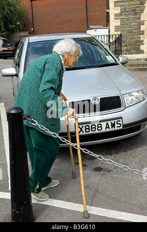 Anziani attivi Inglese 92 anno vecchia donna camminare da solo in un parcheggio con le canne Foto Stock