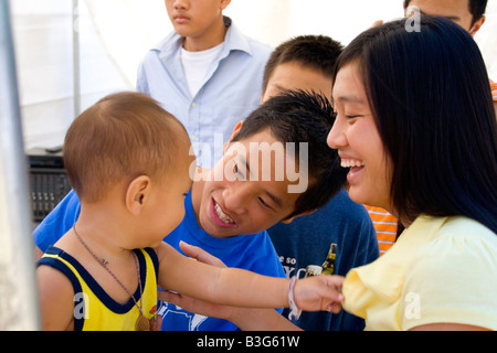 Hmong mamma e papà allietare figlio dopo essere stata trattata nella cura della salute tenda. Hmong Sports Festival McMurray campo St Paul Minnesota USA Foto Stock