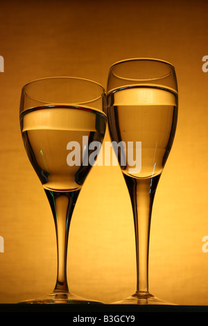 Due dimensioni differenti bicchieri da vino riempito di liquido e disposta su una scatola di legno Foto Stock