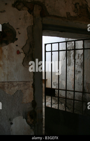 Una vecchia prigione abbandonati cella con barra in metallo porta Foto Stock