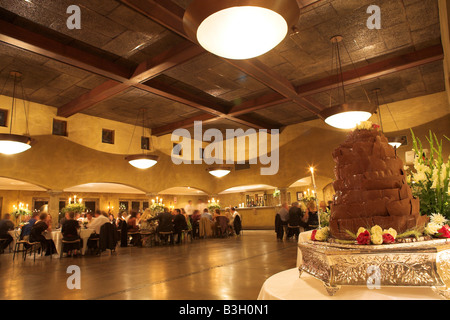 Layered cioccolato torta di nozze su un piatto d'argento nella parte anteriore di un ricevimento di matrimonio hall immagine grandangolare leggera distorsione Foto Stock