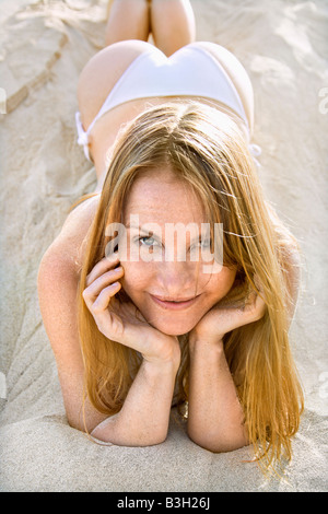 Ritratto di bella femmina redheaded giacente in sabbia indossando un bikini Foto Stock