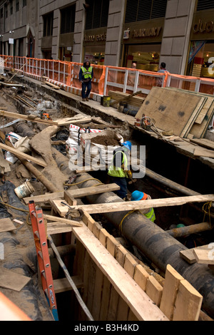 Lavorare sotto Beaver Street sulle infrastrutture nel quartiere finanziario di New York City Foto Stock