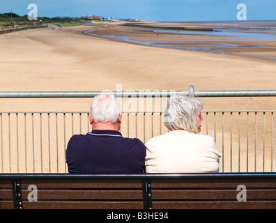 Coppia senior turisti godendo della vista sulla spiaggia da Skegness Pier, da dietro, Lincolnshire, England Regno Unito Foto Stock