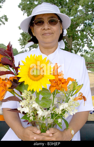 Donna asiatica detiene il bel bouquet orange tiger gigli e un girasole. Dragon Festival Lago Phalen Park St Paul Minnesota USA Foto Stock