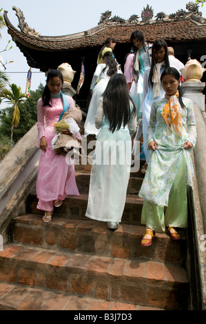 Un gruppo di ragazze vietnamita che indossano il tradizionale Ao dai discendenti del costume i passi della Pagoda su un Pilastro Hanoi Vietnam Foto Stock