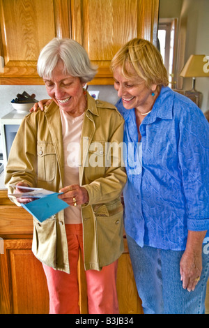 Persone di mezza età ben wishers a 50 anno vecchia donna s festa di compleanno sfogliando le loro hostess cartoline di compleanno modello di rilascio Foto Stock