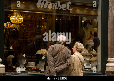 Una coppia di anziani guarda nella finestra della tradizionale ombrellone e hat shop nella Royal St Hubert gallerie, Bruxelles, Foto Stock