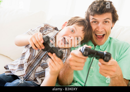 Uomo e ragazzo con i video game controller sorridente Foto Stock