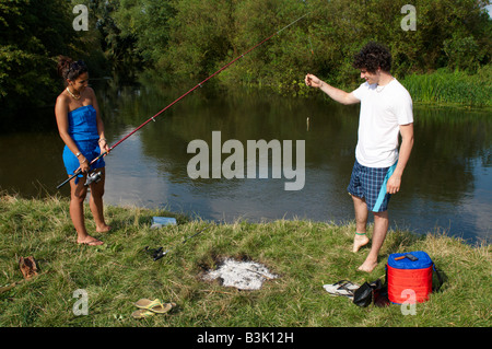 Giovani divertendosi e in posa per la fotocamera con un pesce ha catturato sul fiume Cam fra Cambridge e Grantchester Foto Stock