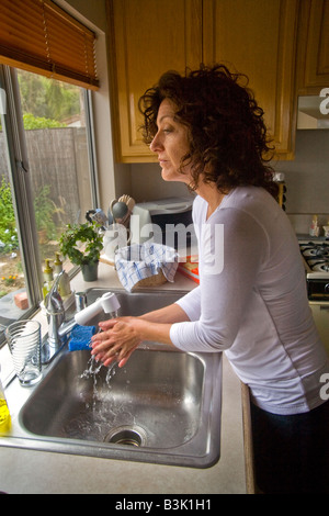 Cinquant'anni di donna vecchia lava le mani nel lavello da cucina a casa in Mission Viejo in California Foto Stock