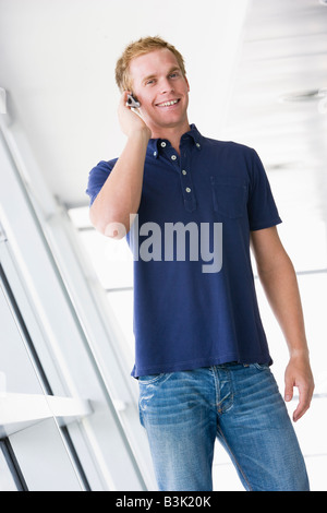 Uomo in piedi nel corridoio che indossa la cuffia sorridente Foto Stock