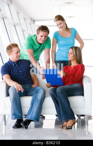 Quattro persone nel lobby e puntando al clipboard sorridente Foto Stock