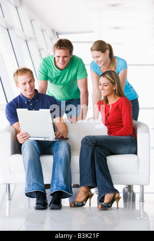 Quattro persone nel lobby e guardando il computer che sorride Foto Stock