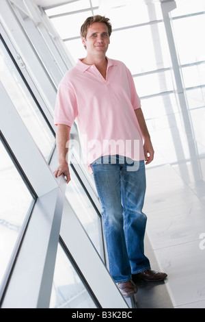 Uomo in piedi nel corridoio sorridente Foto Stock