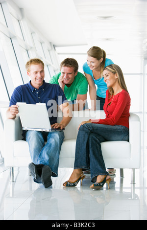 Quattro persone nel lobby e guardando il computer che sorride Foto Stock