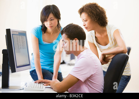 Tre persone sedute in sala computer guardando il monitor Foto Stock