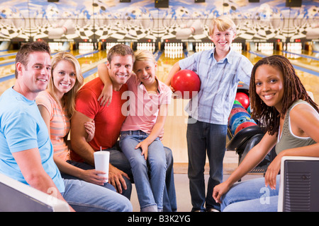 Famiglia in pista da bowling con due amici sorridente Foto Stock