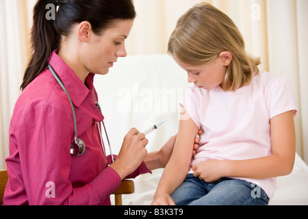 Medico dando ago al giovane ragazza in sala esame Foto Stock