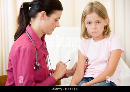 Medico dando ago al giovane ragazza in sala esame Foto Stock