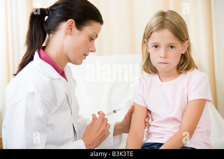 Medico dando ago al giovane ragazza in sala esame Foto Stock