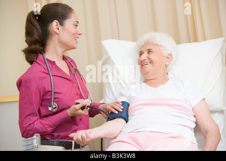 Controllo medico donna della pressione del sangue in sala esame sorridente Foto Stock