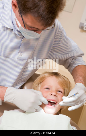 Dentista in sala esame con un giovane ragazzo in sedia Foto Stock