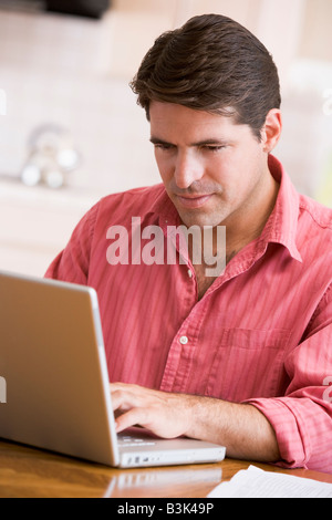 Uomo in cucina utilizzando laptop Foto Stock