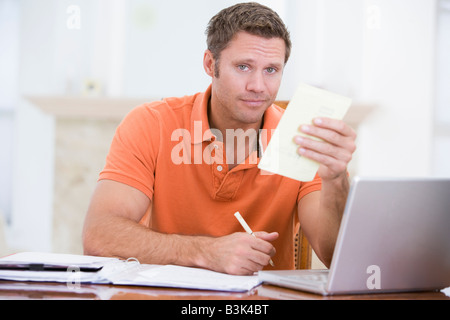 Uomo in sala da pranzo con notebook tenendo la documentazione Foto Stock