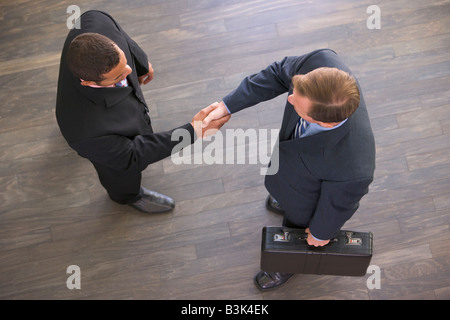 Due uomini d'affari interni stringono le mani Foto Stock