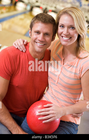 Matura in bowling alley tenendo palla e sorridente Foto Stock