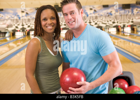 Matura in bowling alley tenendo palla e sorridente Foto Stock