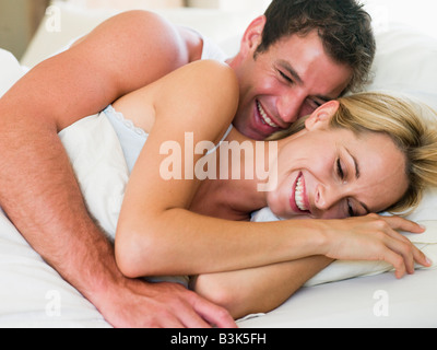 Coppia giacendo nel letto di ridere Foto Stock
