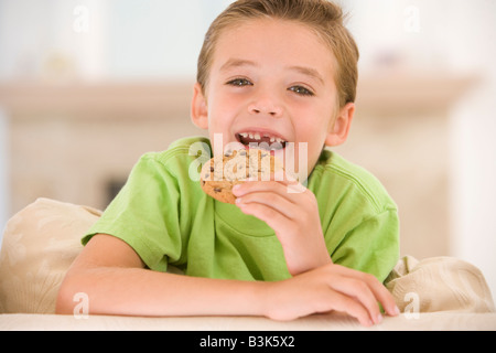 Ragazzo giovane mangiare cookie nel soggiorno sorridente Foto Stock