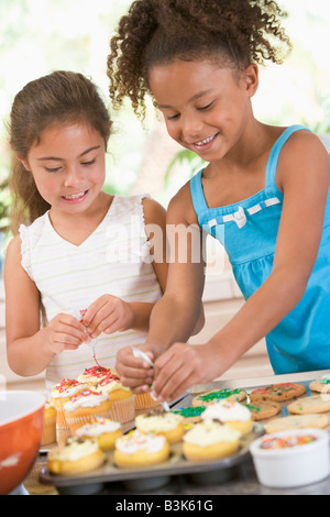 Due bambini in cucina decorare i cookie sorridente Foto Stock