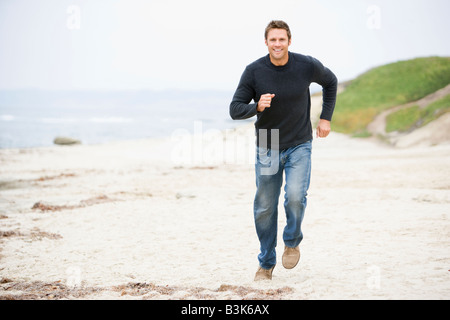 Uomo che corre a beach sorridente Foto Stock